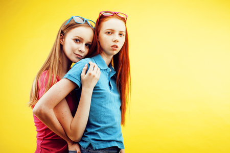 lifestyle people concept: two pretty young school teenage girls having fun happy smiling on yellow backgroundの写真素材