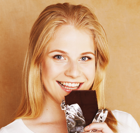young cute blond girl eating chocolate and drinking coffee closeの写真素材