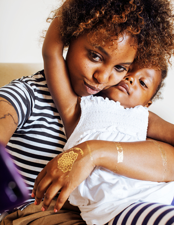 adorable sweet young afro-american mother with cute little daughter, hanging at home, having fun playing smiling, lifestyle people concept, happy smiling modern familyの写真素材