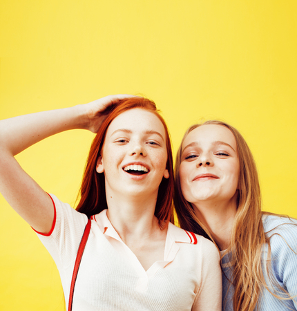 lifestyle people concept: two pretty young school teenage girls having fun happy smiling on yellow backgroundの写真素材