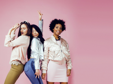 different nation girls with diversuty in skin, hair. Asian, scandinavian, african american cheerful emotional posing on pink background, woman day celebration, lifestyle people conceptの写真素材