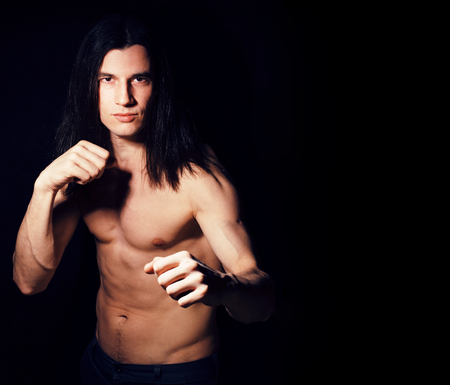 handsome young man with long hair naked torso on black backgrounの写真素材