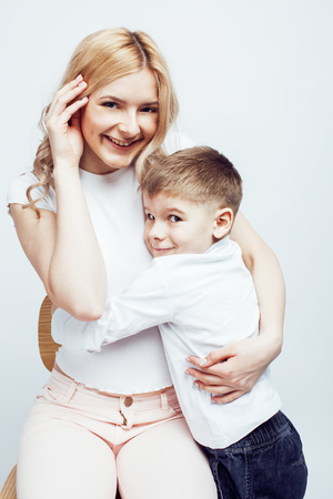 young modern blond curly mother with cute son together happy smiling family posing cheerful on white background, lifestyle people concept, sister and brother friendsの写真素材
