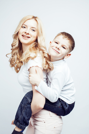 young modern blond curly mother with cute son together happy smiling family posing cheerful on white background, lifestyle people concept, sister and brother friendsの写真素材
