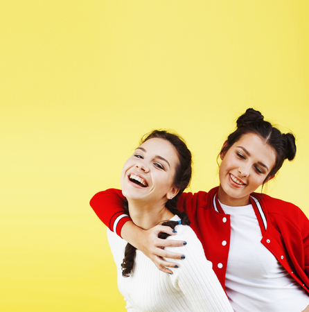 lifestyle people concept: two pretty young school teenage girls having fun happy smiling on yellow backgroundの写真素材