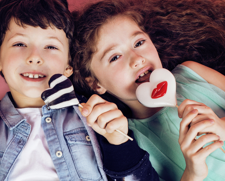 lifestyle people concept: diverse nation children playing together, caucasian boy with african little girl holding candy happy smilingの写真素材