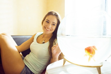 pretty woman playing with goldfish at home, sunlight morningの写真素材