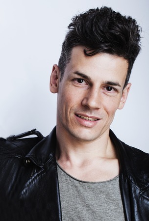 young handsome man, leather jacked on naked torso, emotional posing, white background, modern guy, lifestyle people conceptの写真素材