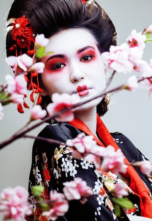 young pretty geisha in kimono with sakura and red decoration design on white backgroundの写真素材