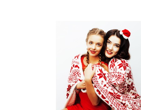 young pretty happy smiling blond and brunette woman girlfriends on christmas in santas red hat and holiday decorated plaid, lifestyle people concept close upの写真素材