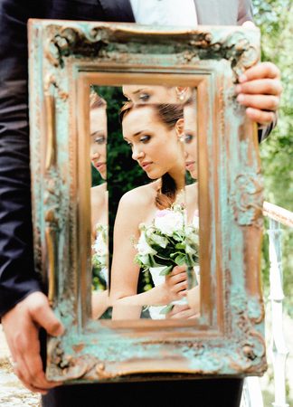 wedding people concept, groom holding vintage mirror with bride reflectionの写真素材