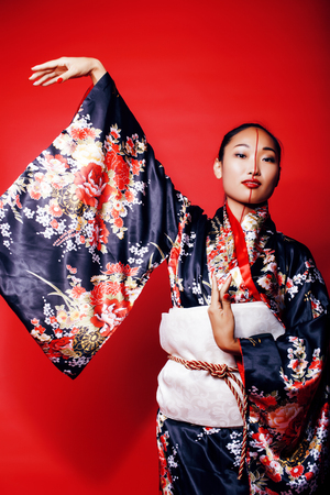 young pretty geisha on red background posing in kimono, oriental people concept close upの写真素材
