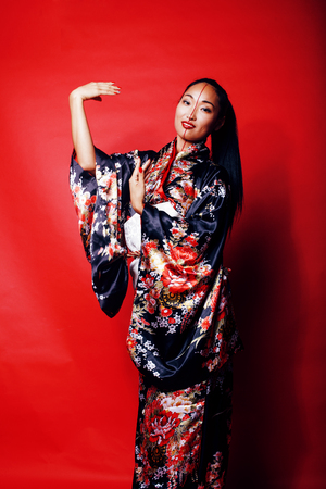 young pretty geisha on red background posing in kimono, oriental people concept close upの写真素材