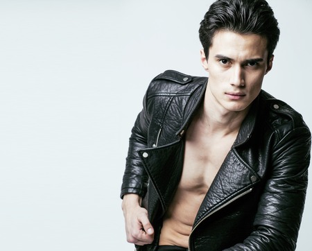 young handsome man, leather jacked on naked torso, emotional posの写真素材