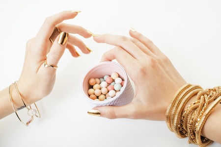 woman hands with golden manicure and many rings holding brushes,