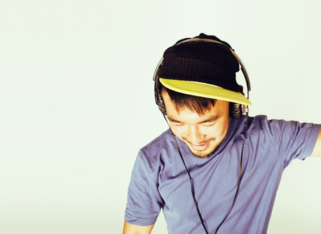 young asian man in hat and headphones listening music on white b