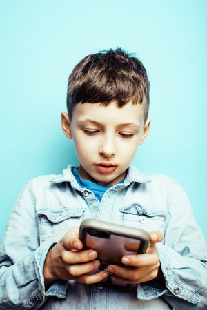 little cute boy posing emotional on blue background with smartphの写真素材