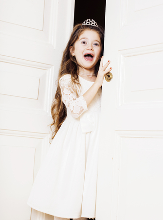 little cute girl at home, opening door well-dressed in white dreの写真素材