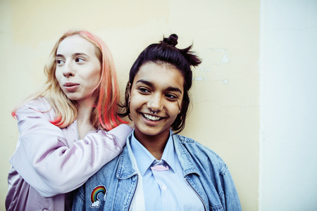 Two teenage girls infront of university building smiling, havingの写真素材