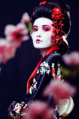 young pretty geisha in kimono with sakura and decoration on blackの写真素材