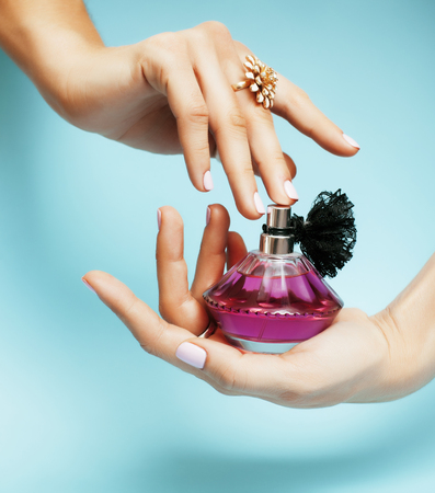 woman hands holding bottle of perfume pink manicure and jewelryの写真素材