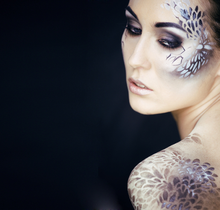 portrait of pretty young woman with creative make up like a snake, fashion victim with python skin...