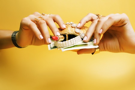 woman hands holding hamburger with money, jewelry, cosmetic, socの写真素材