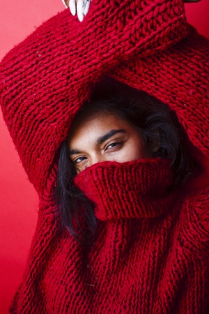 young pretty indian mulatto girl in red sweater posing emotionalの写真素材