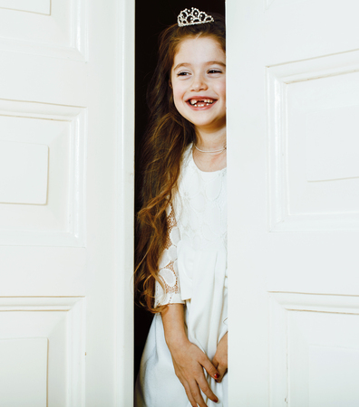 little cute girl at home, opening door well-dressed in white dreの写真素材