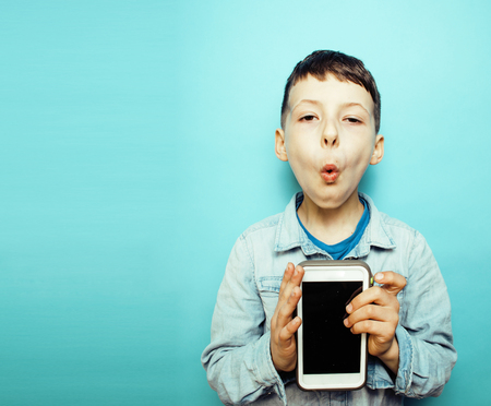little cute boy posing emotional on blue background with smartphの写真素材
