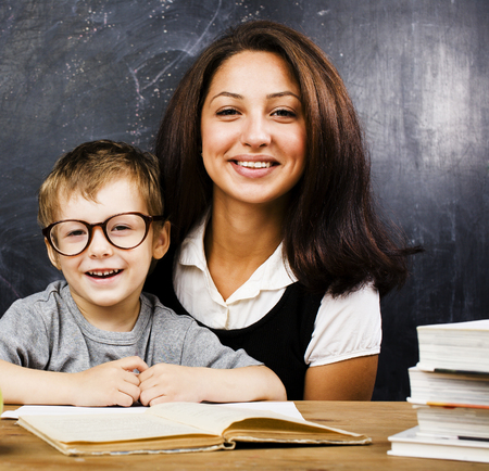 little cute boy in glasses with young real teacher, classroom studyingの写真素材