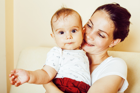 young brunette happy mother holding toddler baby son, breast-feeの写真素材