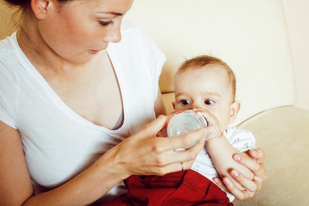 young brunette happy mother holding toddler baby son, breast-fee
