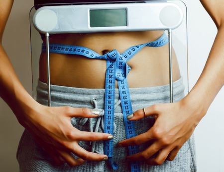 woman measuring waist with tape on knot like a gift, african tanの写真素材