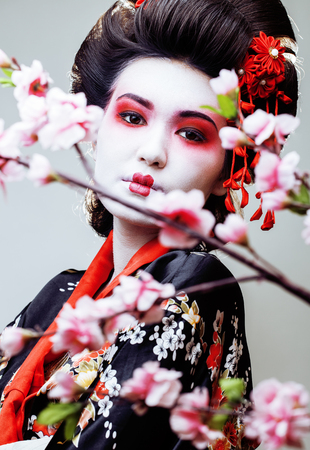 young pretty geisha in black kimono among sakura, asian ethnicの写真素材