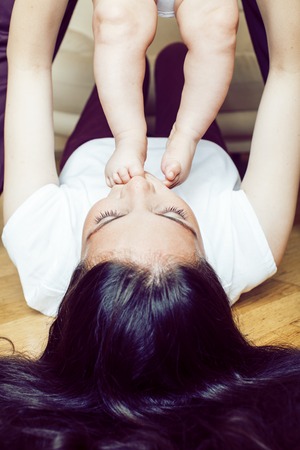 young brunette happy mother holding toddler baby son, breast-feeの写真素材