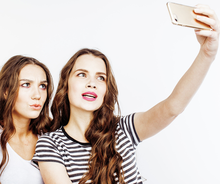 two best friends teenage girls together having fun, posing emotional on white background, besties happy smiling, making selfie, lifestyle people conceptの写真素材