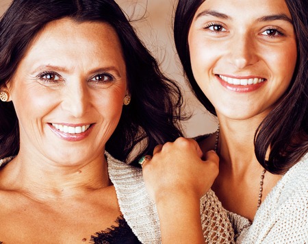 cute pretty teen daughter with mature mother hugging, fashion stylish brunette closeupの写真素材
