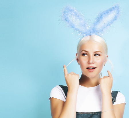 young pretty blond girl with rabbit ears posing cheerful on blue background, lifestyle people conceptの写真素材