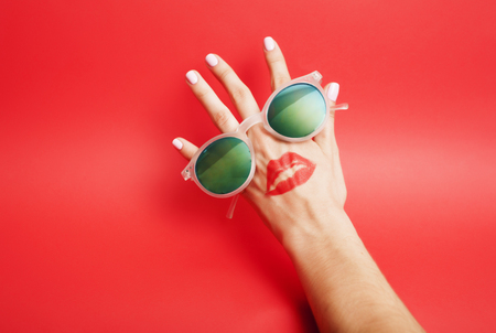 woman hand holding sunglasses on bright background, cosmetic summer vacation concept close upの写真素材