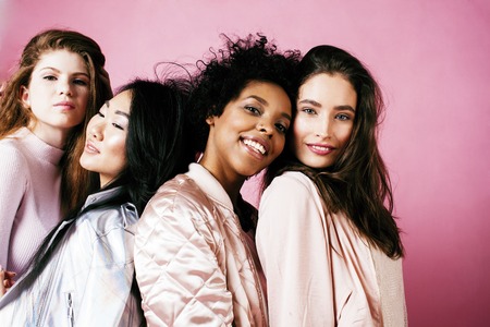 different nation girls with diversuty in skin, hair. Asian, scandinavian, african american cheerful emotional posing on pink background, woman day celebration, lifestyle people concept close upの写真素材