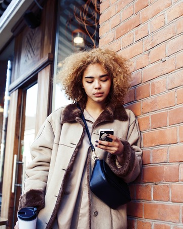 young pretty african american women drinking coffee outside in cafe, modern business woman lifestyle conceptの写真素材