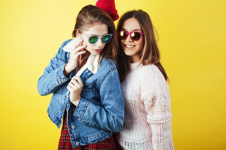 lifestyle people concept: two pretty young school teenage girls having fun happy smiling on yellow background close upの写真素材