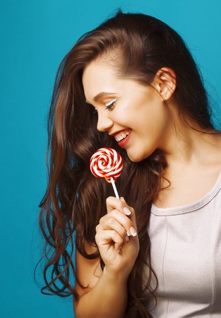 young pretty brunette woman posing happy cheerful on blue background with candy, lifestyle people conceptの写真素材