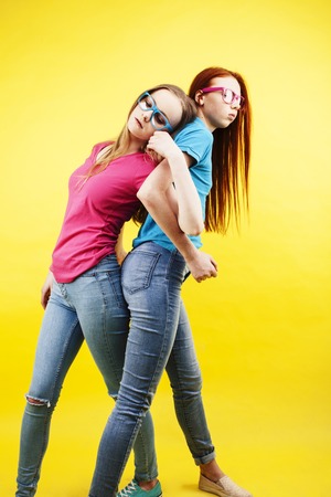 lifestyle people concept: two pretty young school teenage girls having fun happy smiling on yellow background close upの写真素材