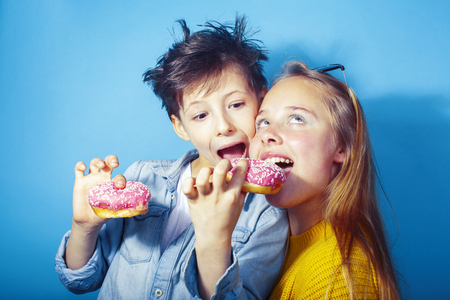 happy family brother and sister eating donuts on blue background, lifestyle people concept, boy and girl eating unhealthyの写真素材