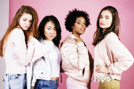 different nation girls with diversuty in skin, hair. Asian, scandinavian, african american cheerful emotional posing on pink background, woman day celebration, lifestyle people concept close upの写真素材