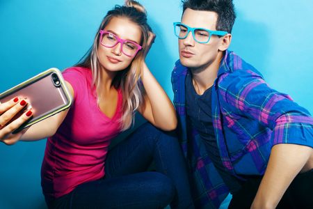 happy couple together posing cheerful on blue background wearing glasses, guy and girl students together friendsの写真素材