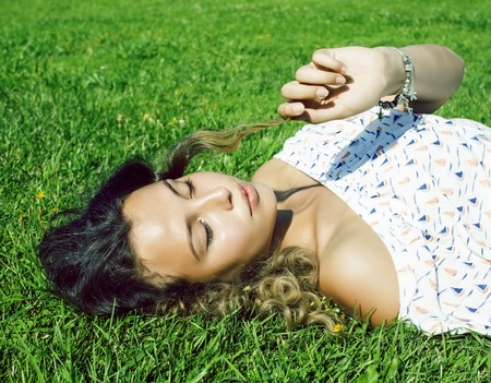 young pretty curly girl smiling cheerful on green grass, lifestyle people conceptの写真素材