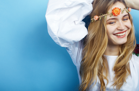 young pretty blond girl posing on blue background, fashion style hippie boho flowers on headの写真素材